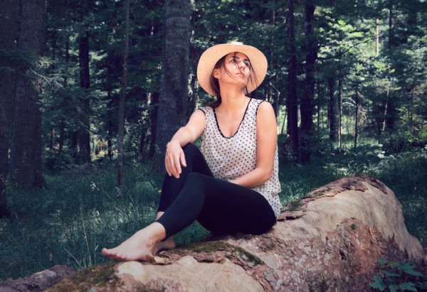 Forest bathing woman relaxing on a fallen tree trunk in the forest.