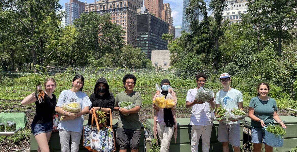 Group of students presenting their harvest in front of The Battery Urban Farm.