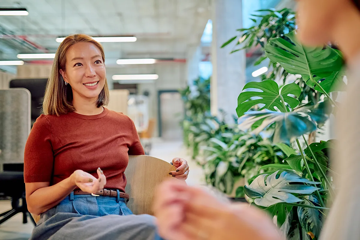 Employees gathering near a green plants, engaging in nature therapy.
