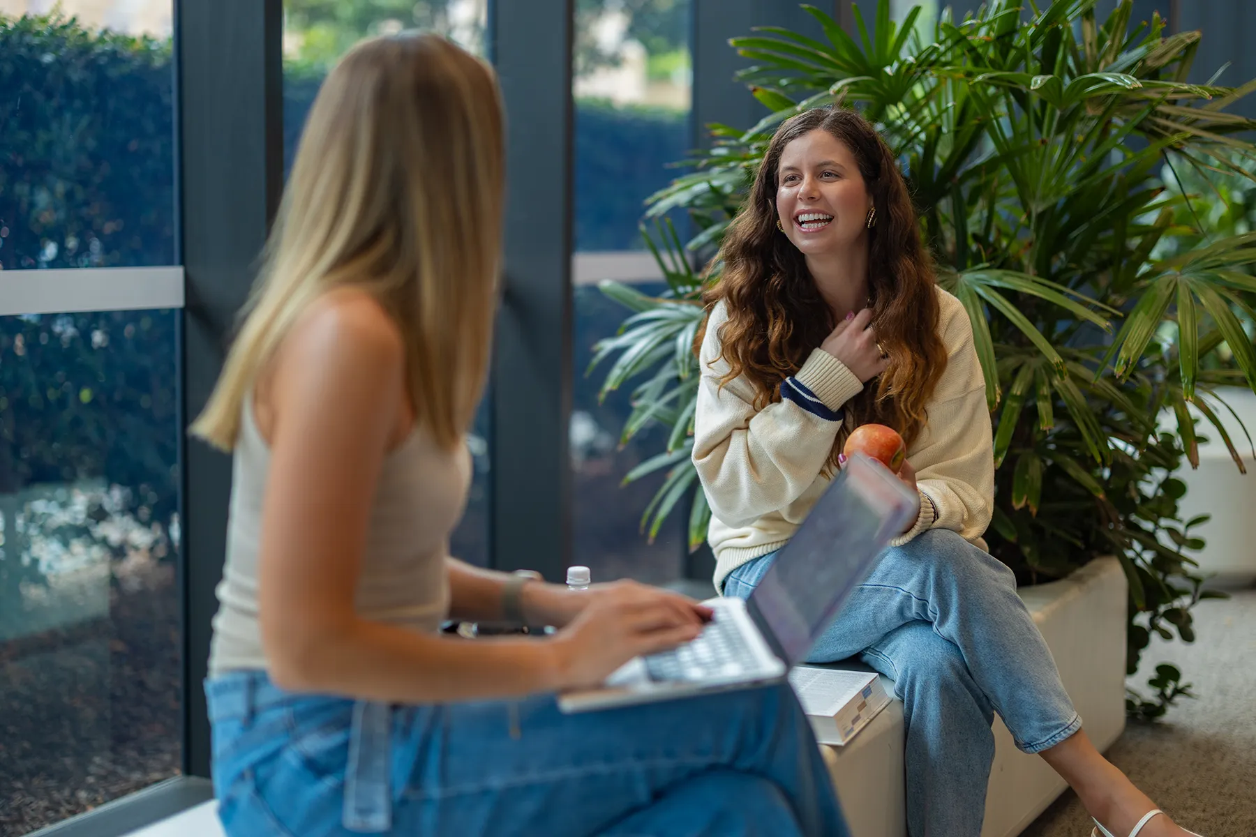 University students studying in an indoor atrium featuring biophilic design elements and abundant plant therapy.