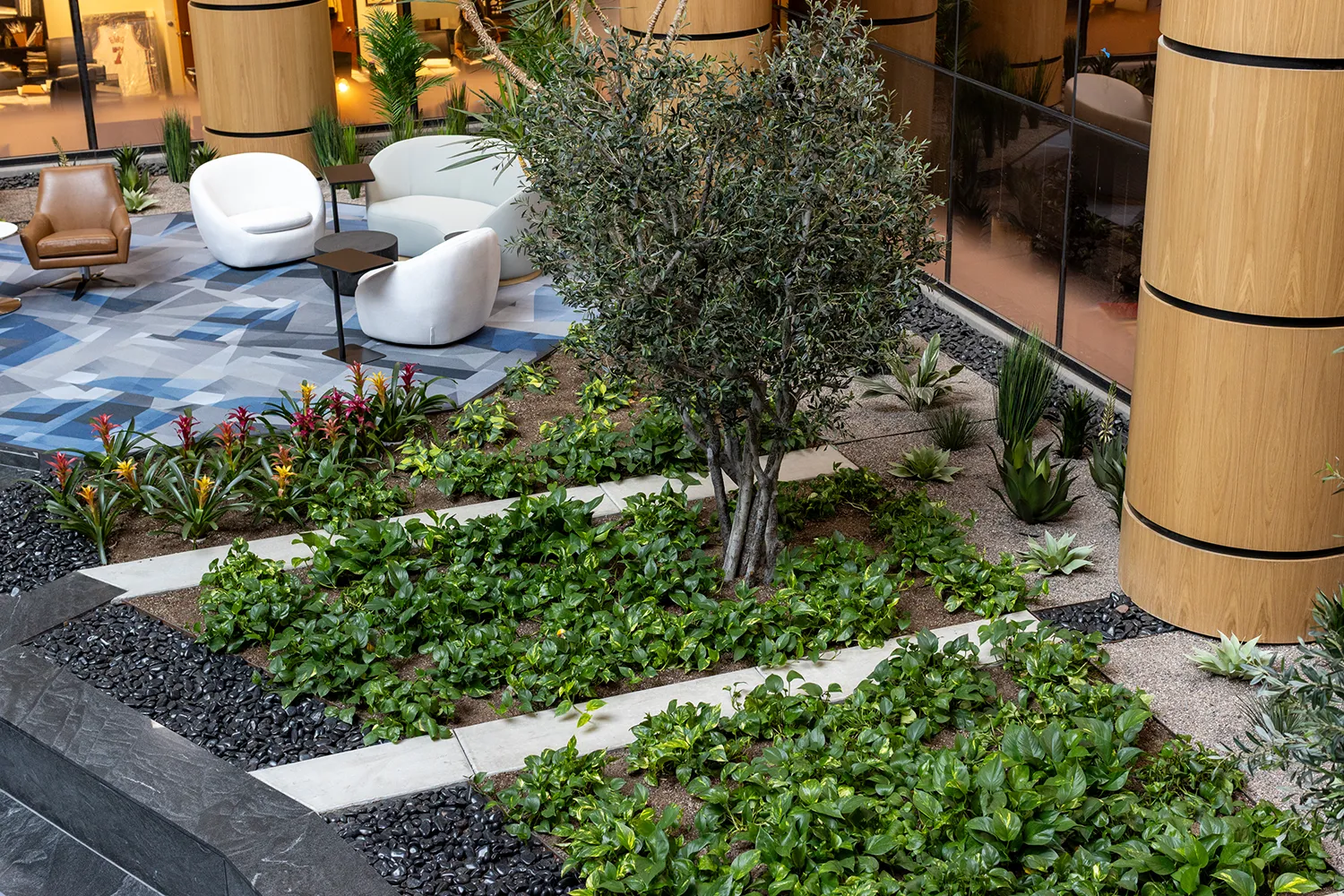 Commercial interiorscape design in a building lobby, showcasing a beautifully landscaped indoor planter area that divides a modern seating space.